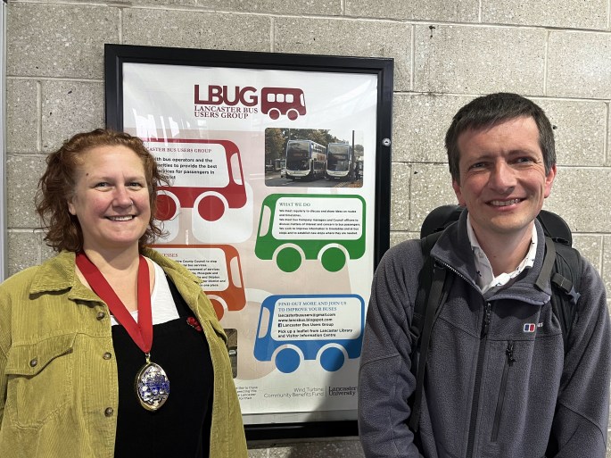 two people standing in front of a notice board